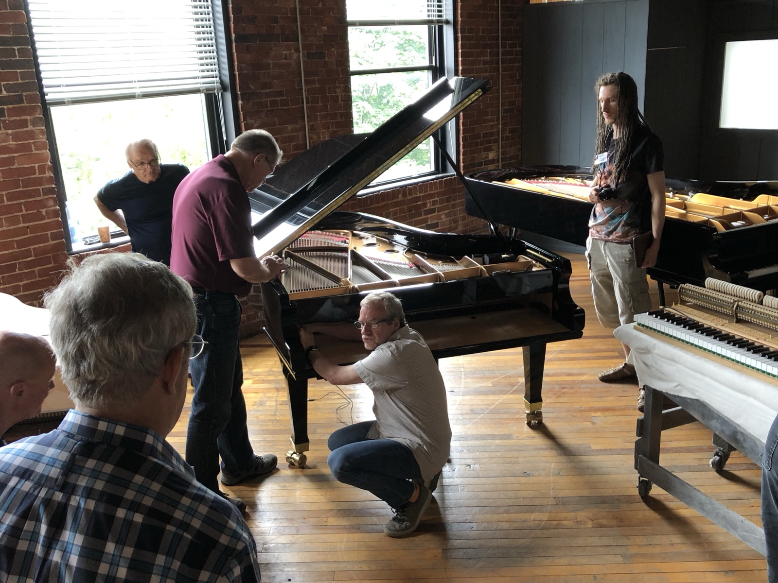 Detailed action work on a grand piano during factory training.
